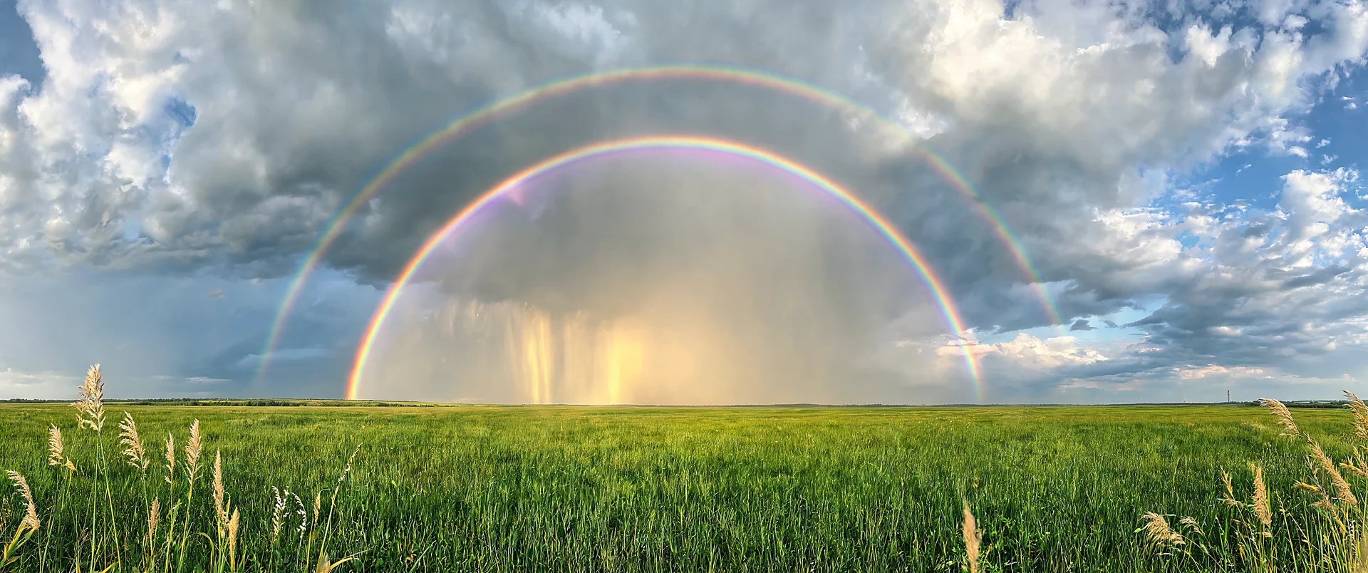 Vibrant rainbow arching over sunlit rain shafts